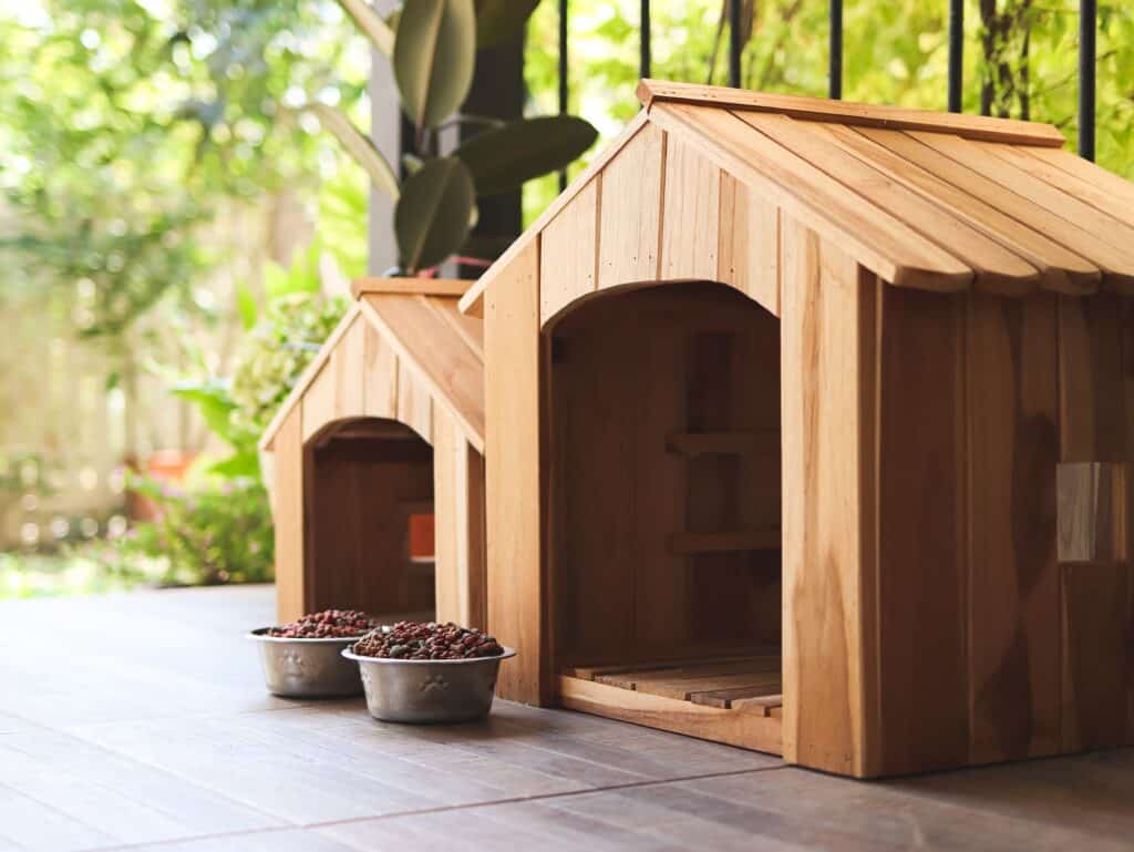 Side View Of Two Empty Wooden Dog'S Houses With Dog Food Bowls In Balcony